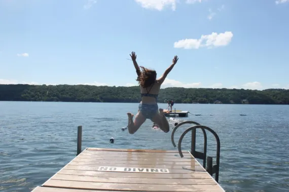 girl jumping off of the dock at camp