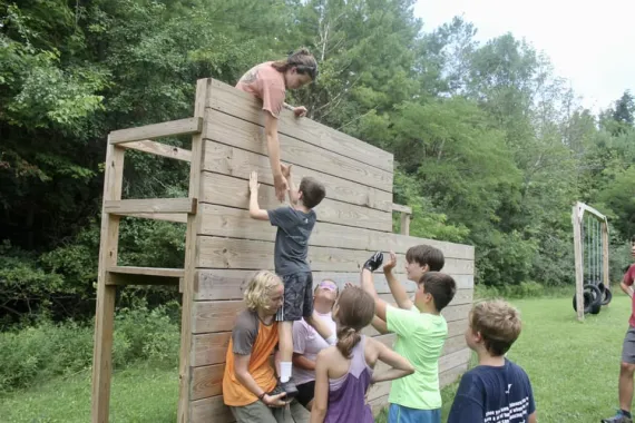 kids helping each other over a wall